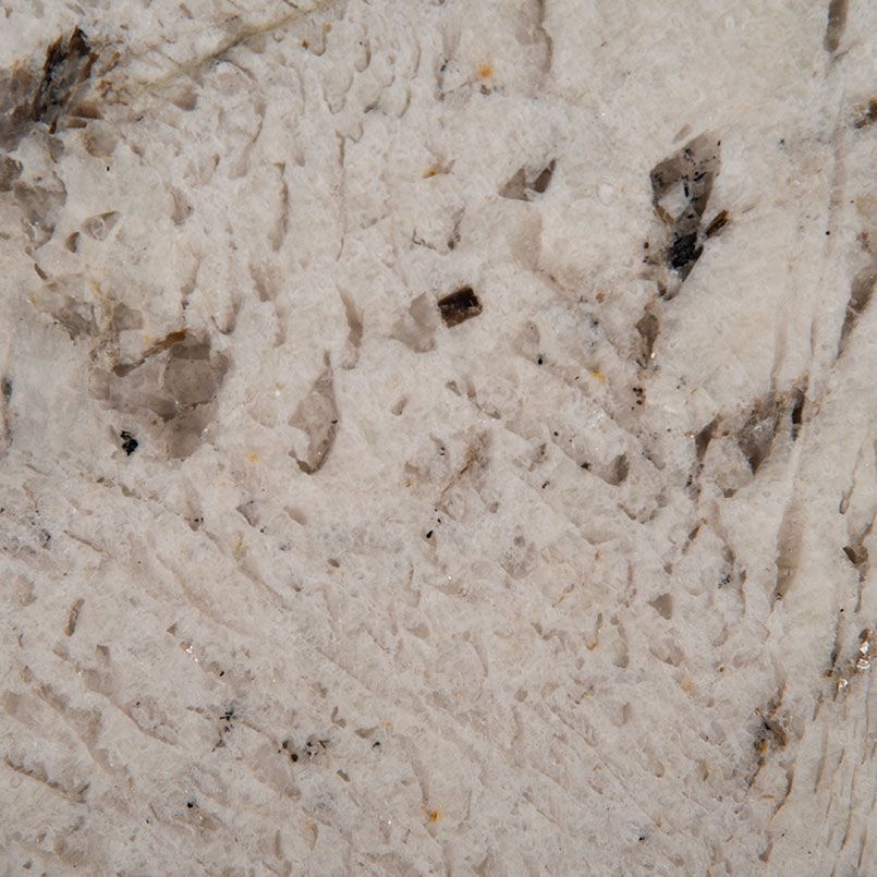Close-up of granite countertop with light beige background and dark flecks.