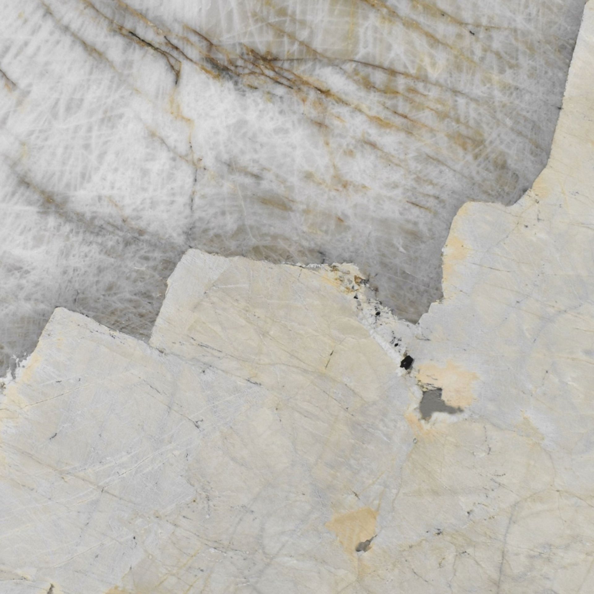 Close-up of a light-colored stone surface with natural veining and irregular edges.