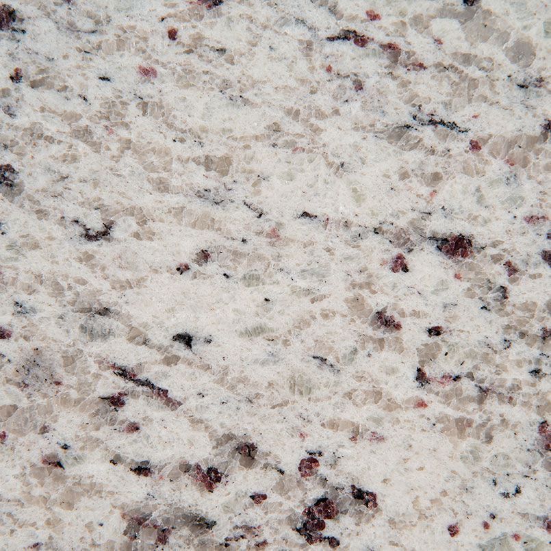Close-up of white granite countertop with flecks of black and burgundy.