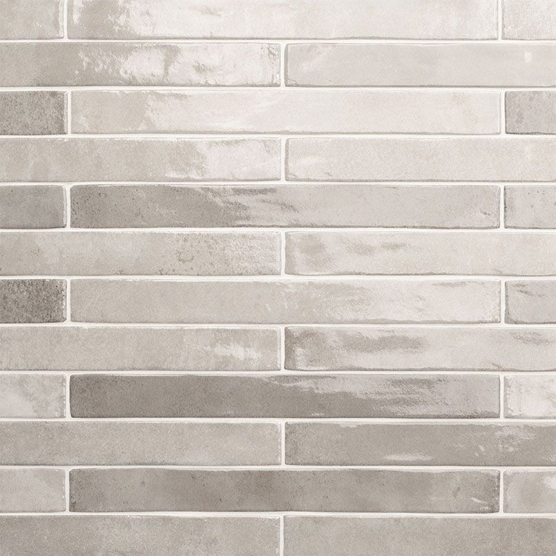 Light gray and off-white brick-style tile wall with varying shades and textures.