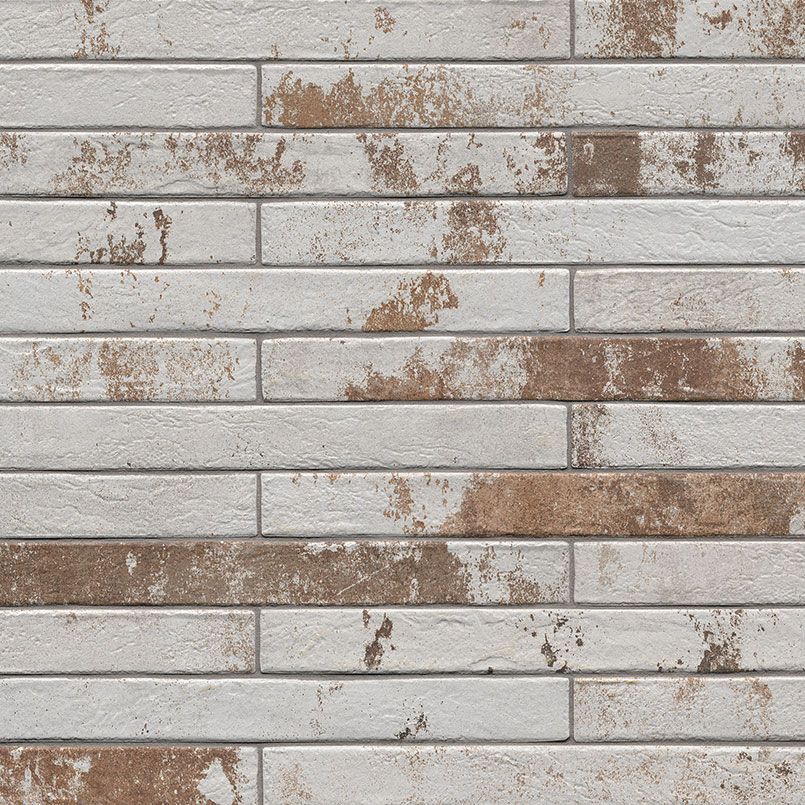 Whitewashed brick wall with brown weathered patches.