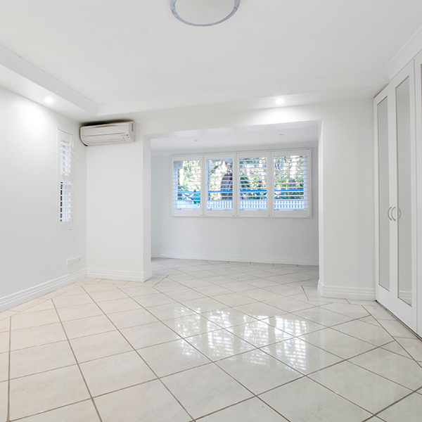 Empty, bright white room with glossy tiled floor, built-in closet, and window with outdoor view.