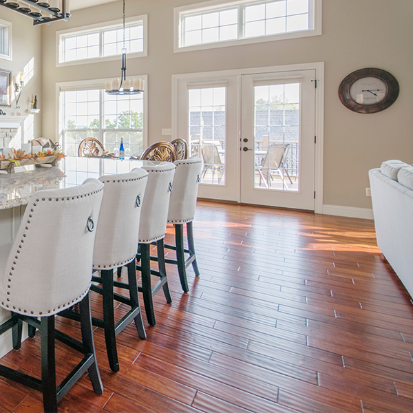 Interior shot of a kitchen and dining area with bar stools, French doors, and hardwood floors.