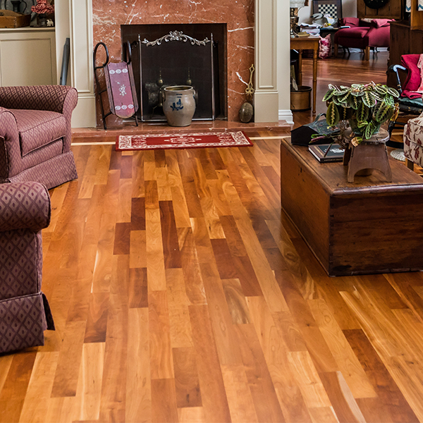 Hardwood floor in a living room, with fireplace, chairs, and a wooden chest.
