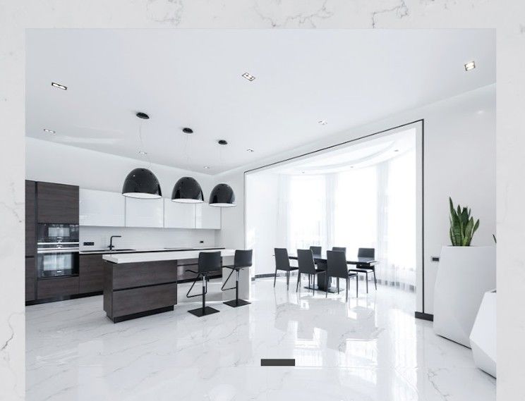 Modern white kitchen with dark wood cabinets and island, black pendant lights, and a dining area.