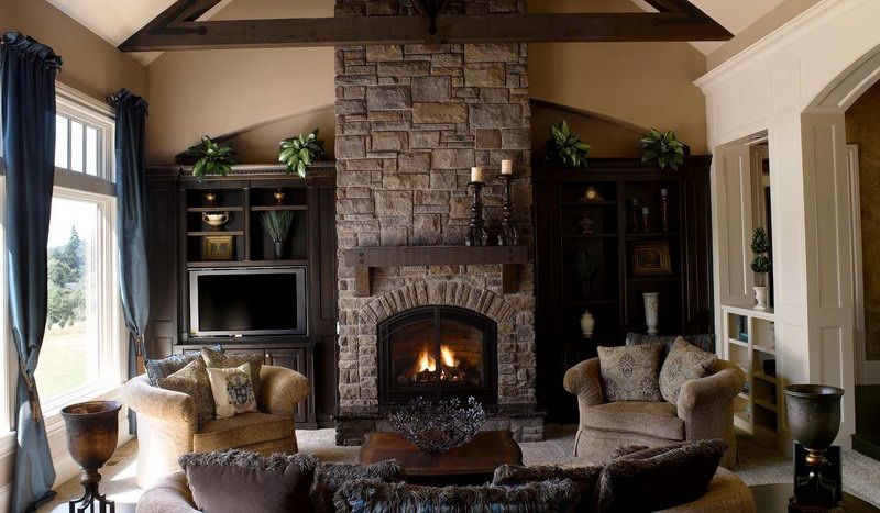 Cozy living room with stone fireplace, dark wood built-ins, and comfortable armchairs.
