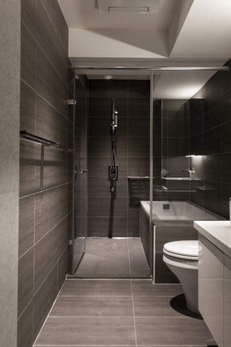 Modern bathroom with dark gray tile walls, glass shower, bathtub, and toilet.