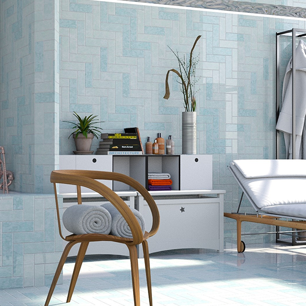 Spa-like bathroom with blue tiled walls, wooden chair, towels, and various toiletries on white shelving.