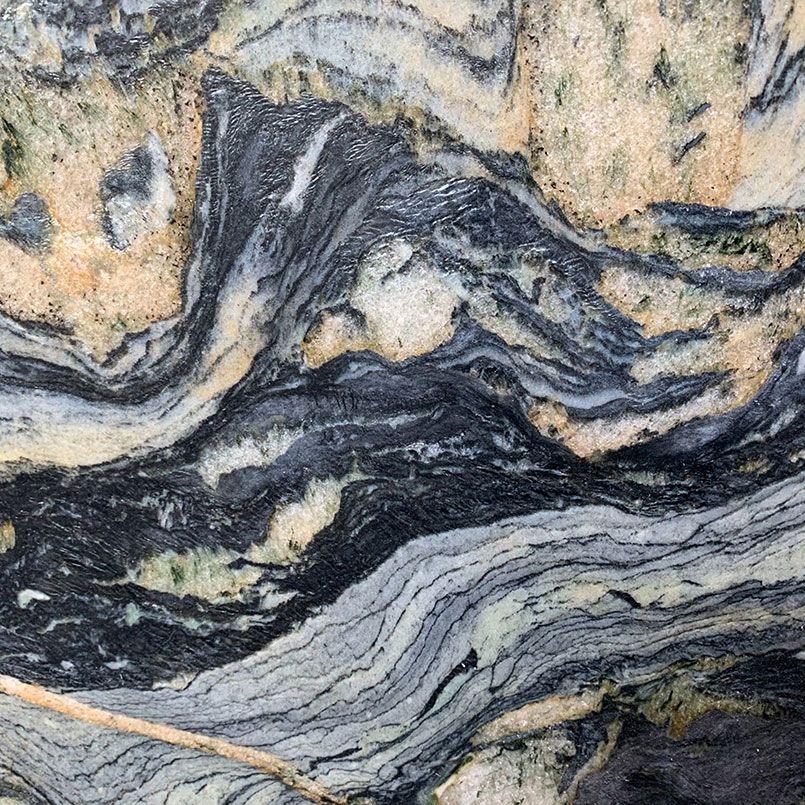 Swirling pattern of granite with black, grey, tan and green colors.