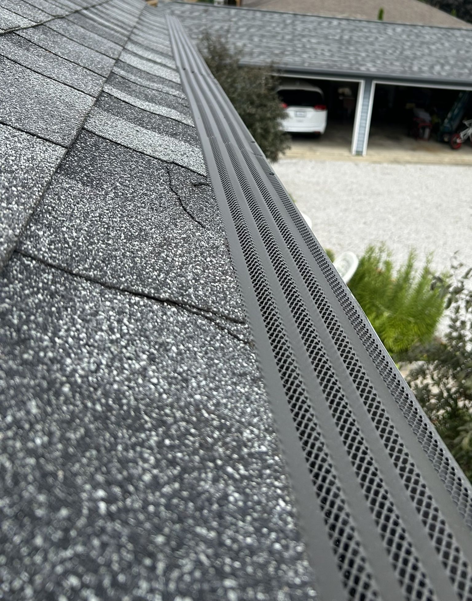 Gray roof with gutter guard; view overlooks driveway and garage.