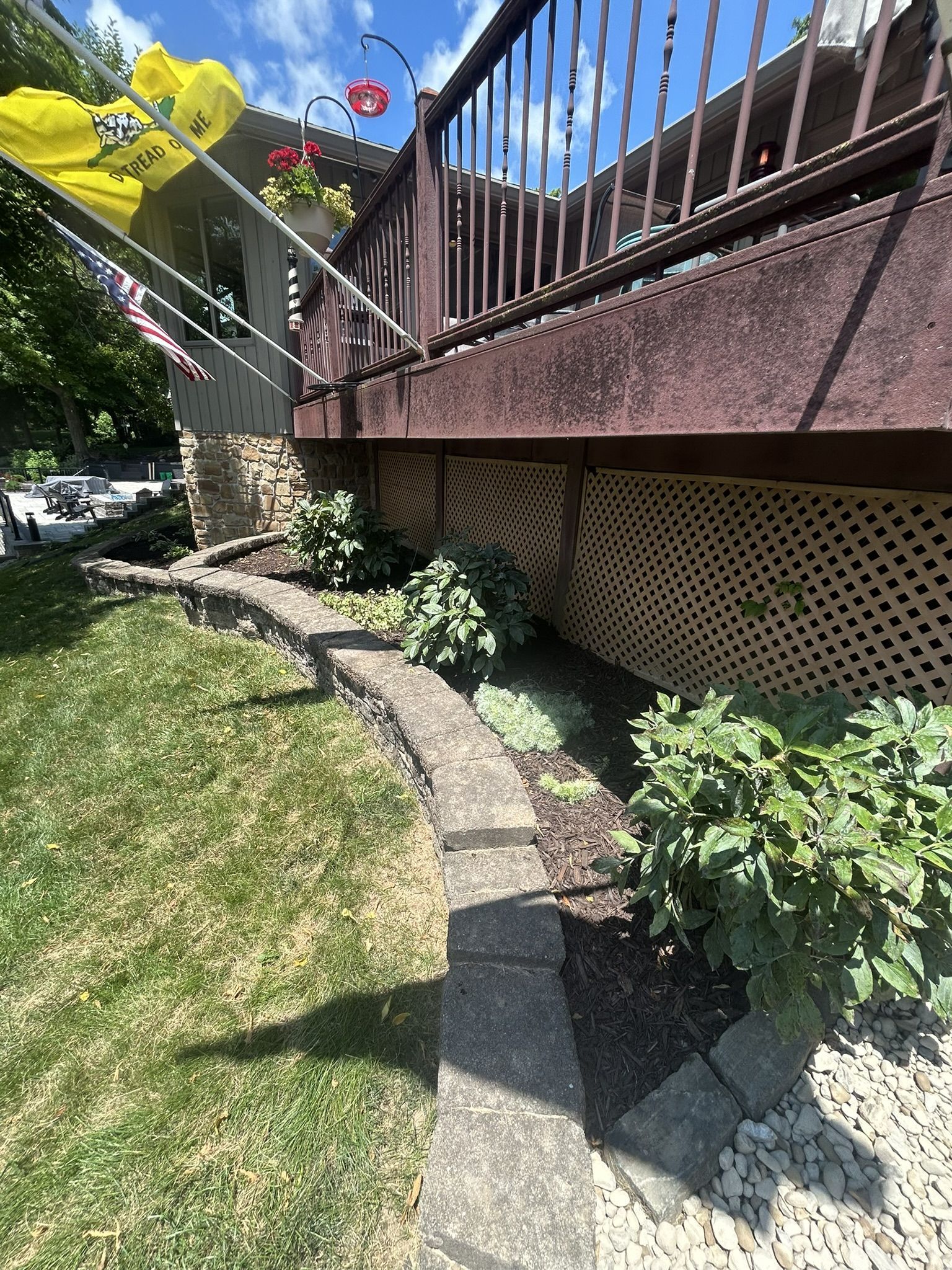 A wooden deck with lattice skirting over a stone pathway and garden.