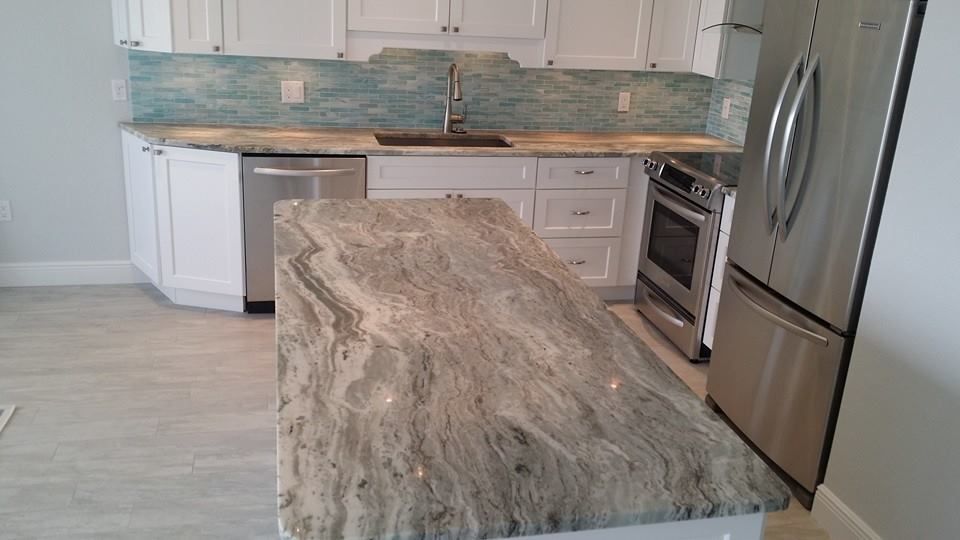 Kitchen with white cabinets, blue backsplash, stainless steel appliances, and a gray patterned island countertop.