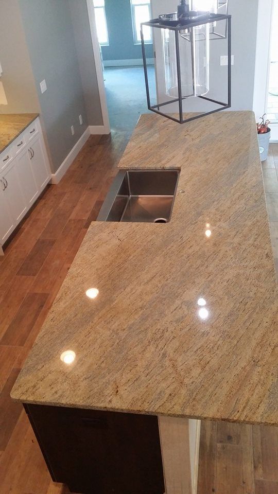 Kitchen island with granite countertop, built-in sink, and dark brown cabinets, set on hardwood floor.