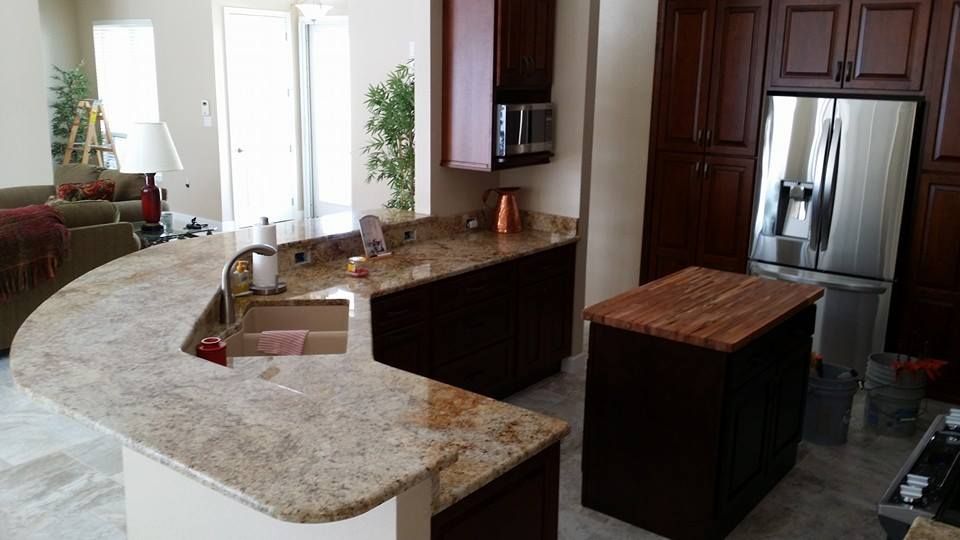 Kitchen with granite countertops, dark brown cabinets, and stainless steel refrigerator.