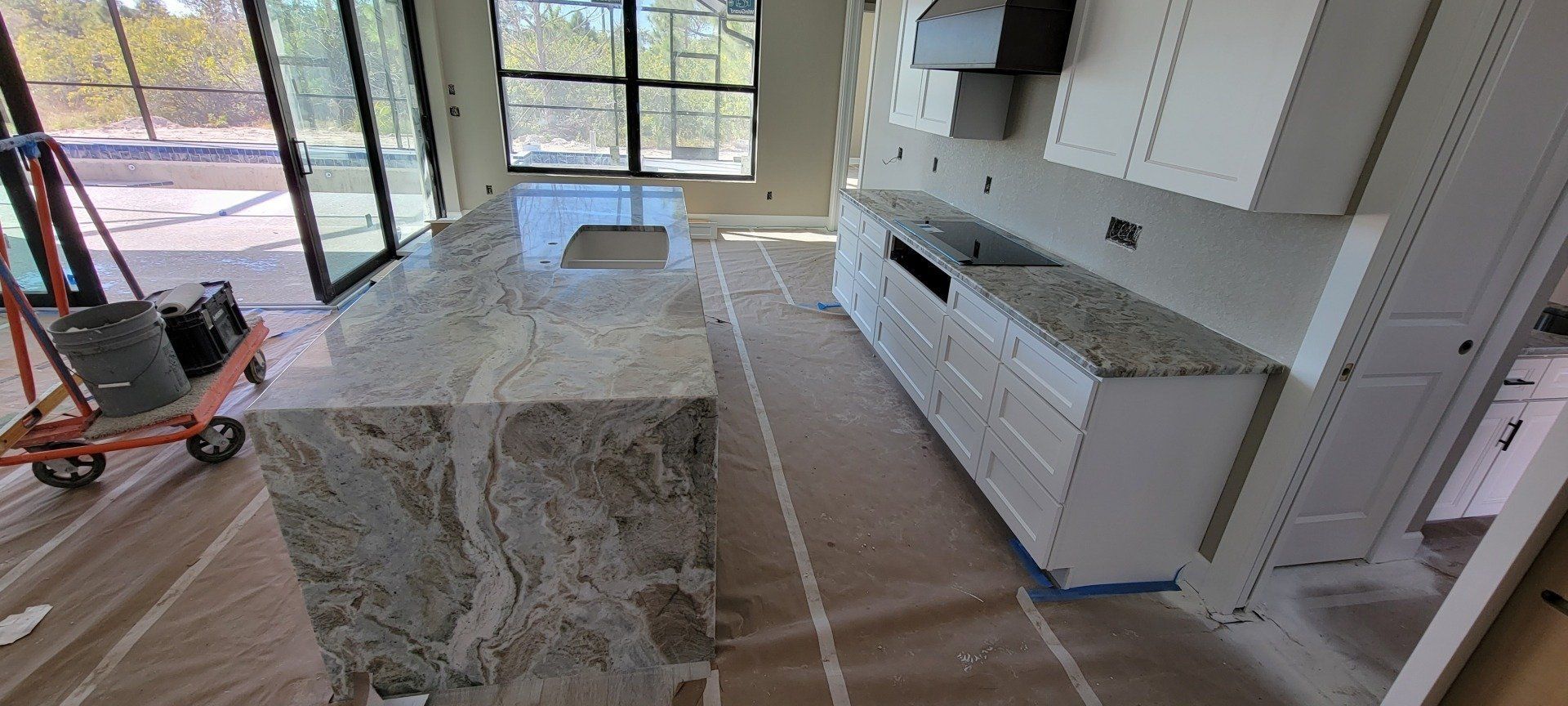 Kitchen under construction with granite countertops and white cabinets.