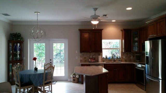 Kitchen with dark wood cabinets, granite countertops, and stainless steel appliances. A small island and a round dining table.