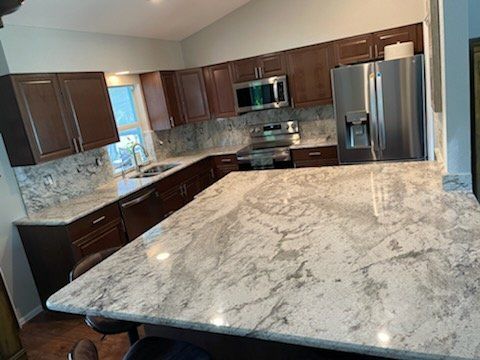 L-shaped kitchen with brown cabinets, granite countertops, and stainless steel appliances.