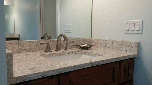Bathroom sink with granite countertop, dark wood cabinet, and brushed nickel faucet.