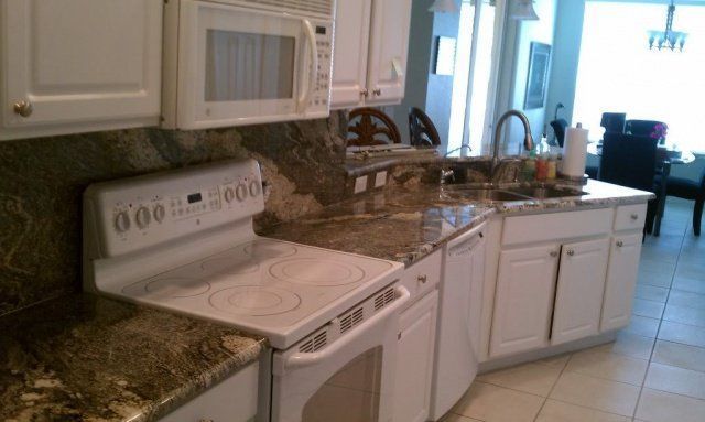 Kitchen with white cabinets, granite countertops, and a white stove.