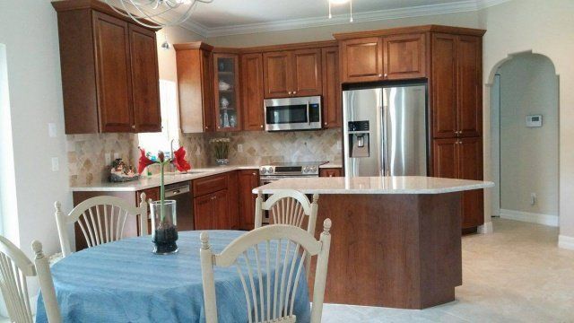 Kitchen with wood cabinets, island, round table, and stainless steel appliances.
