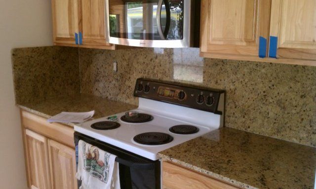 Kitchen with light wood cabinets, speckled countertops, and a white stove.