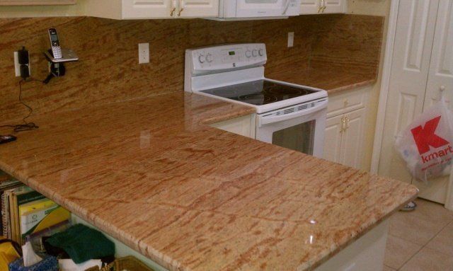 Kitchen with granite countertops and white stove, cabinets, and appliances. A Kmart bag hangs on a door.