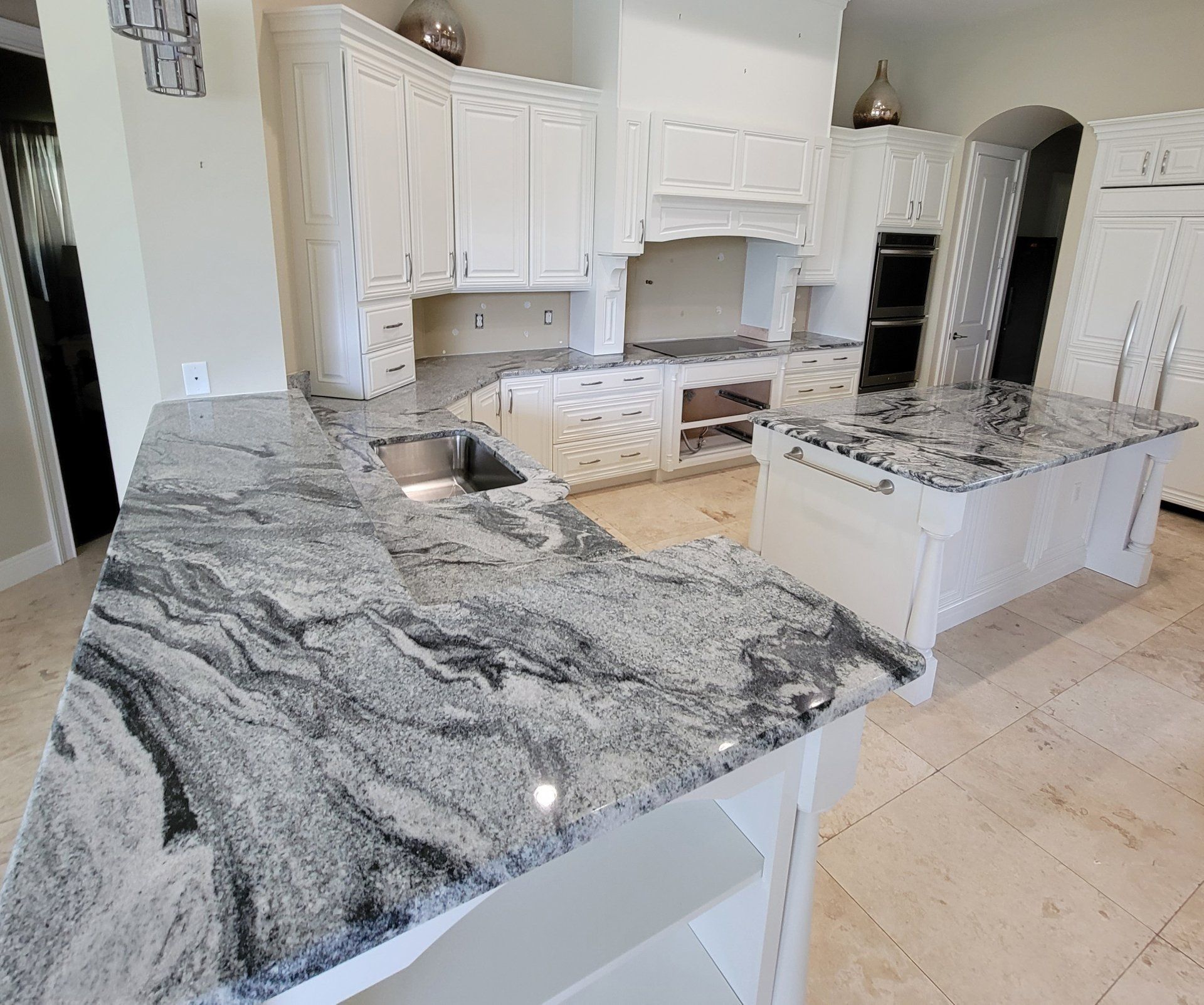 Kitchen with white cabinets and granite countertops; a stainless steel sink is in the corner.