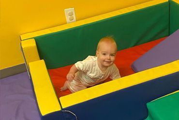 A baby is crawling through a colorful foam pit