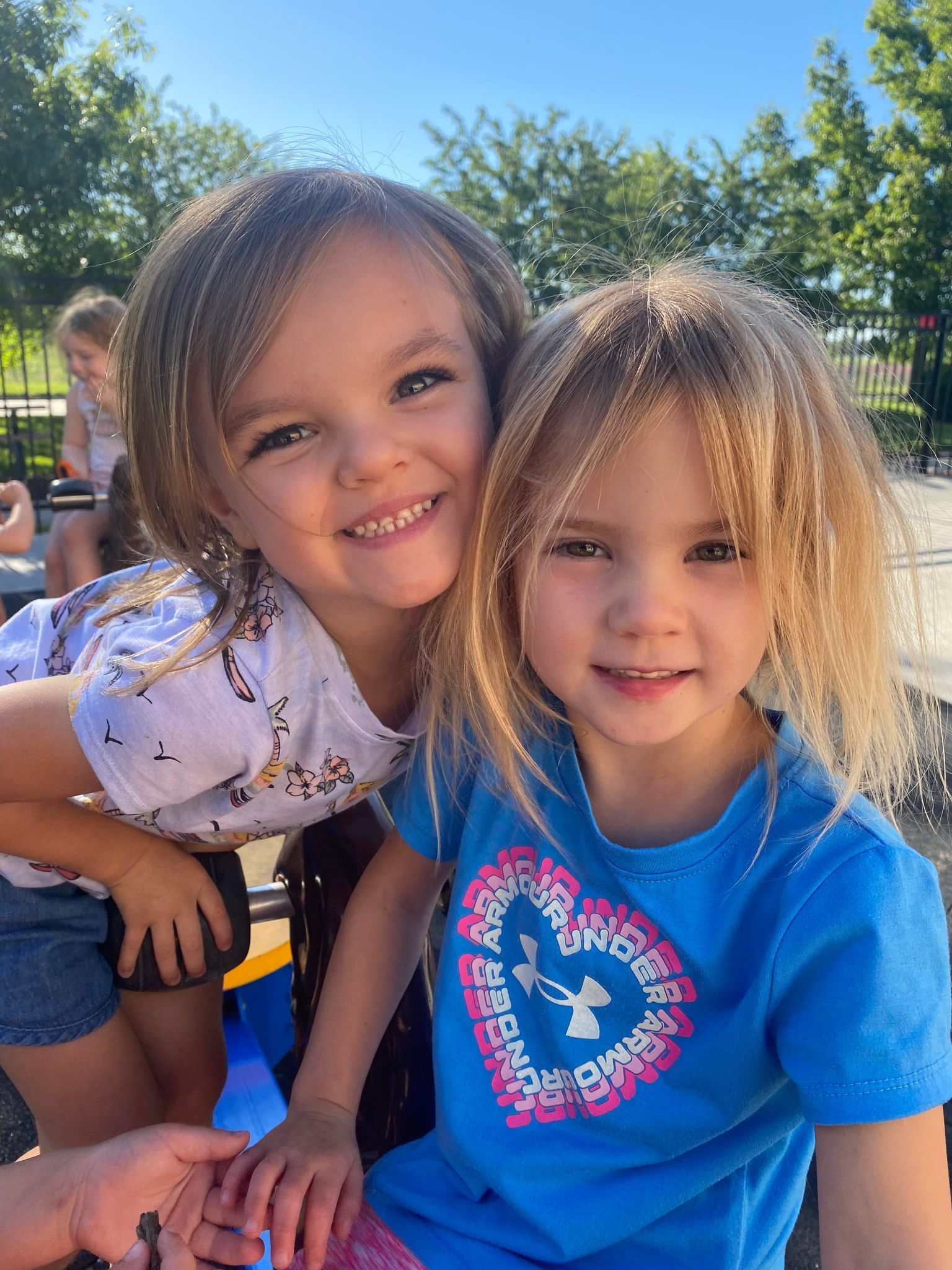 Two little girls are sitting next to each other and smiling for the camera.