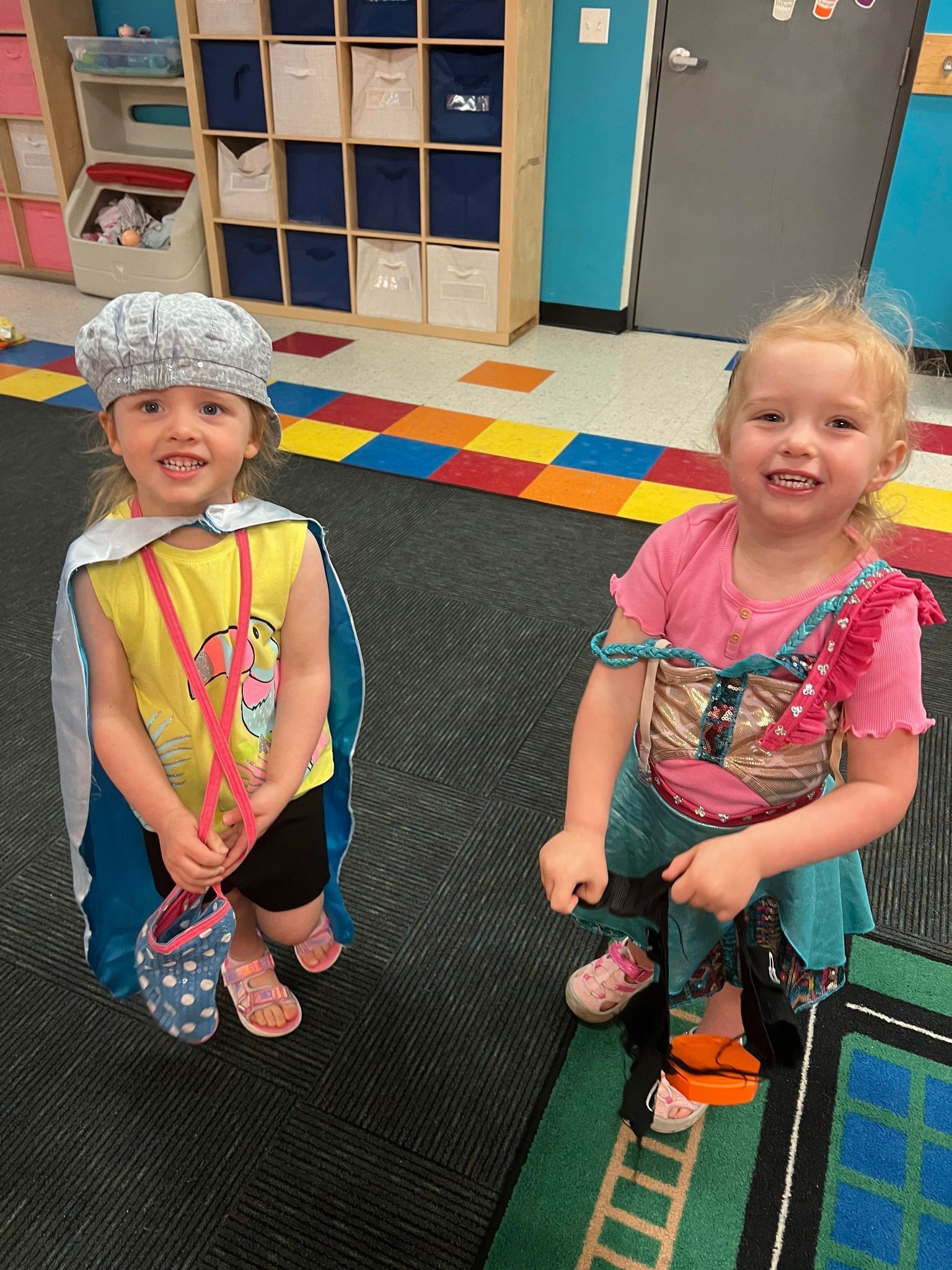 Two little girls are dressed up in costumes in a classroom.