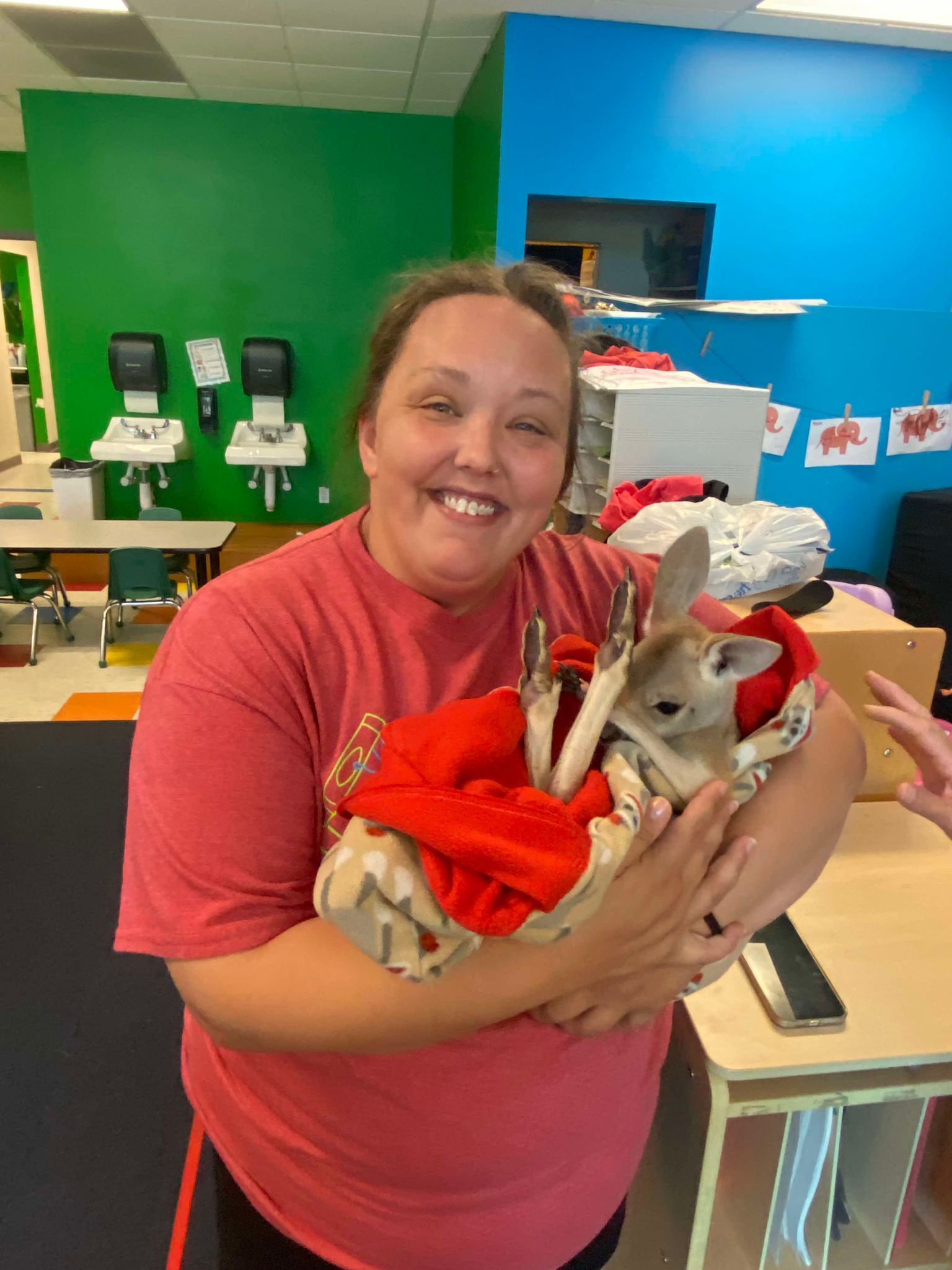 A woman is holding a small animal in her arms.