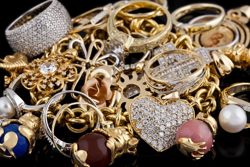 Pile of various gold and silver jewelry, including rings, necklaces, and pendants.