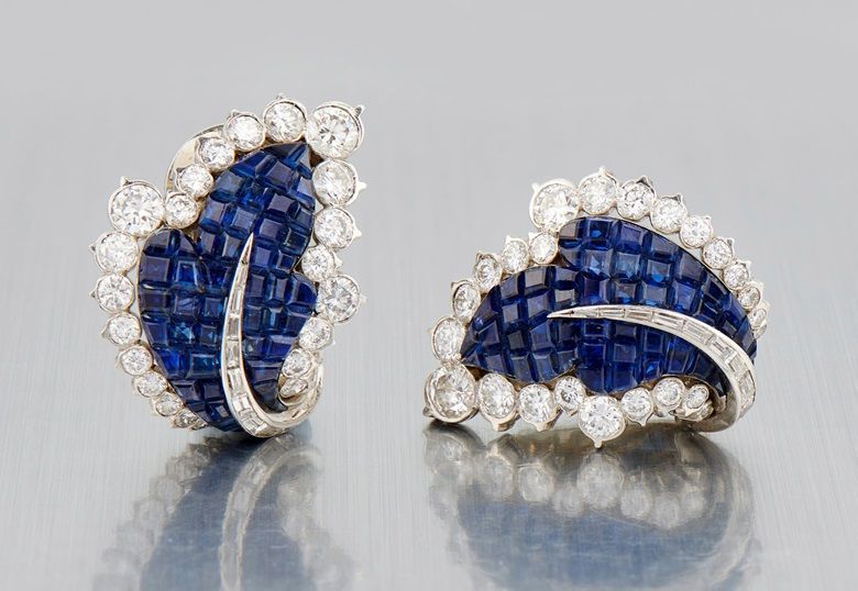 A pair of sapphire and diamond earrings on a table.