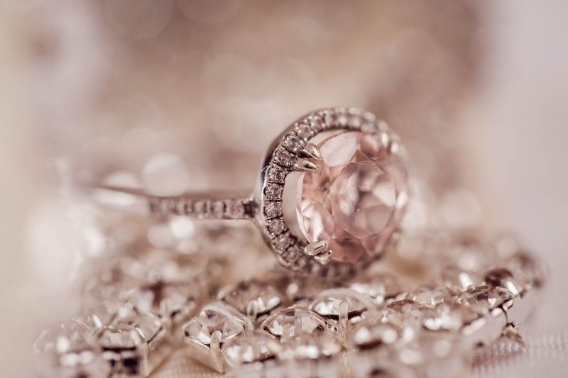 A close up of a ring sitting on top of a pile of diamonds.