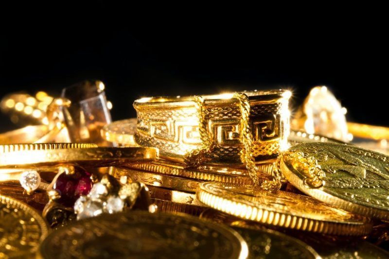 A pile of gold coins and jewelry on a black background.