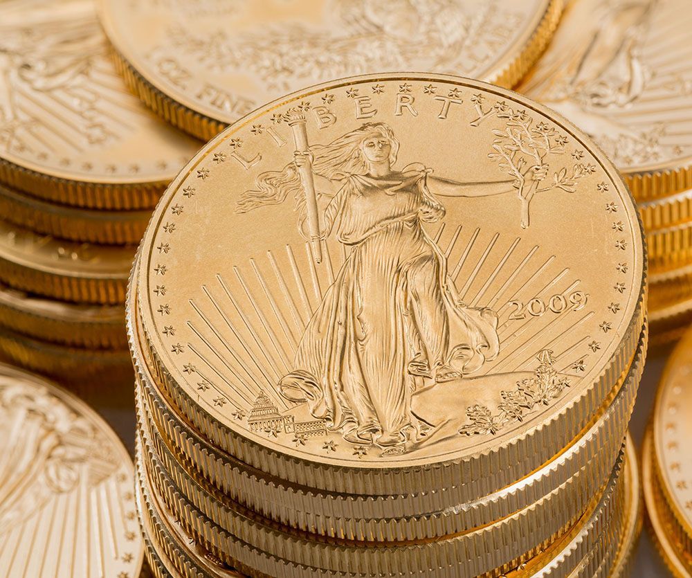 Stacks of gold coins, U.S. gold eagles, depicting Lady Liberty and the sun's rays.