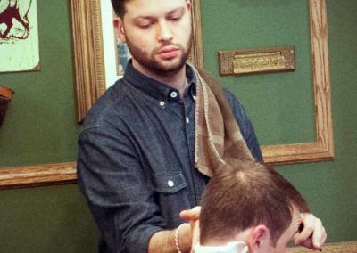 A man is getting his hair cut by a barber in a barber shop.