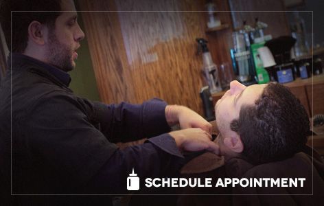 A man is getting his beard shaved by a barber in a barber shop.