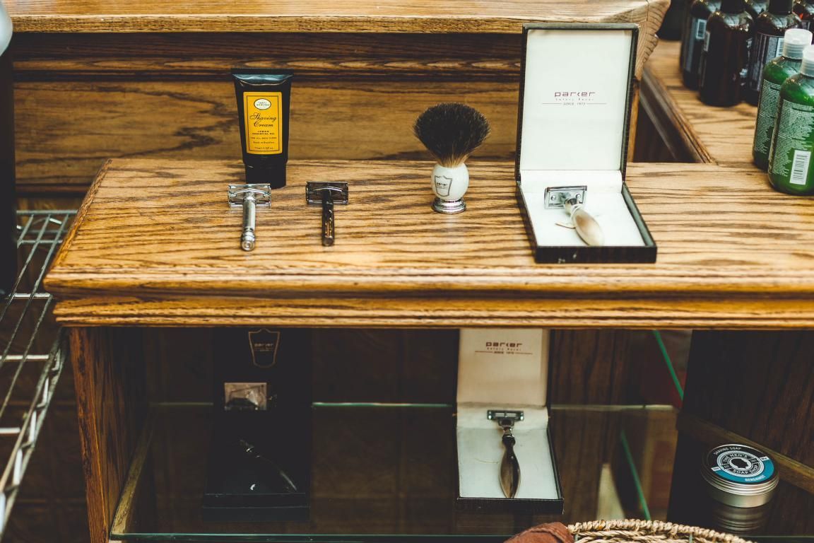 A wooden table with a shaving razor and a shaving brush on it.