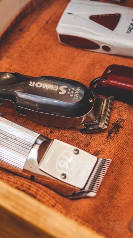 A bunch of hair clippers are sitting on a wooden table.