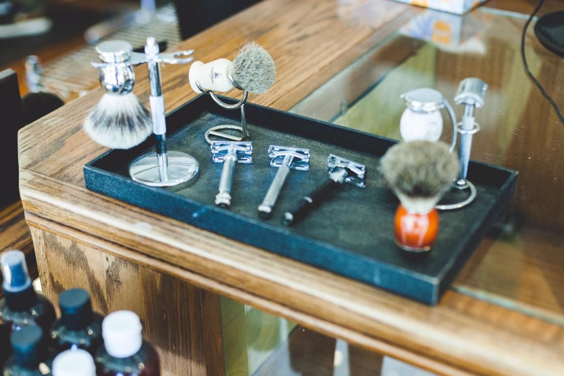 A tray with razors and brushes on it is on a table.