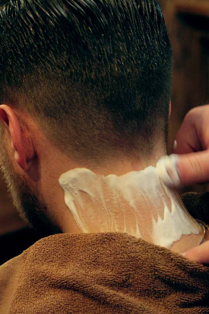 A man is getting his neck shaved by a barber.