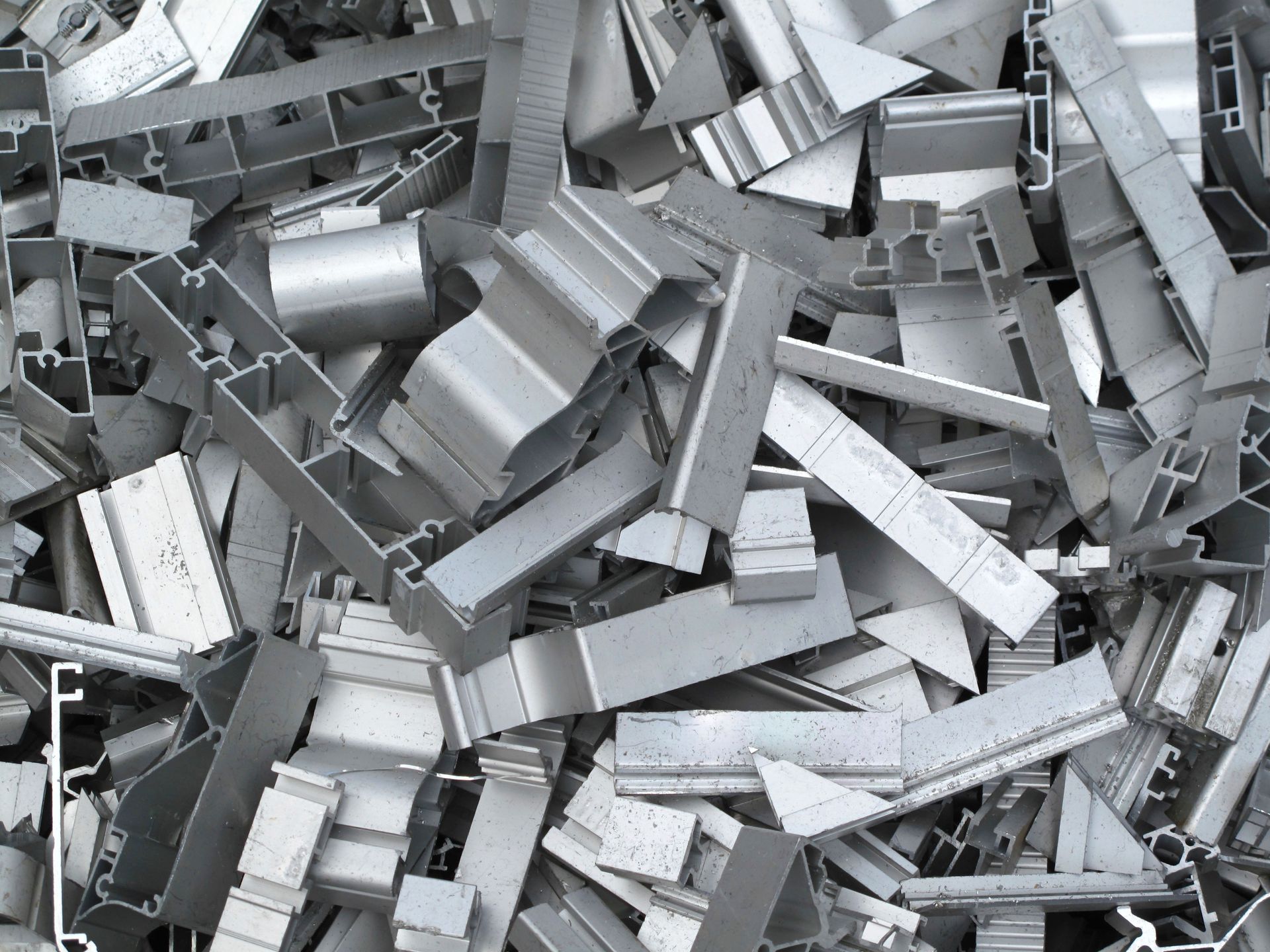 Scrap aluminum pieces, a pile of various shapes and sizes, ready for recycling.