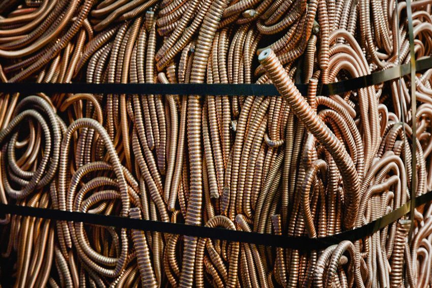 Bundle of coiled copper wire, bound with black straps, ready for recycling.