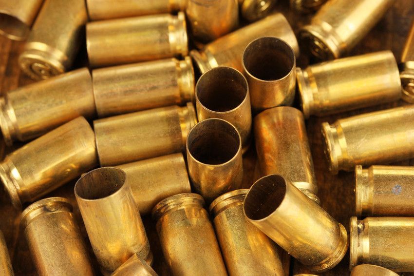 Spent brass shell casings, many gold-colored, scattered on a surface.