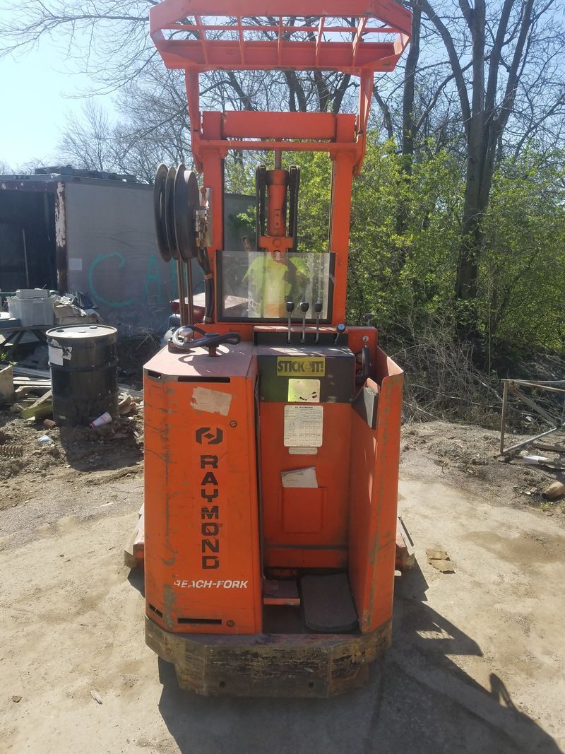 Orange Raymond narrow aisle forklift. Outdoors on concrete.