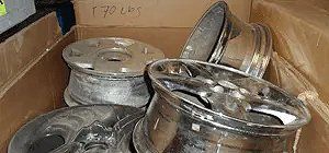 Four chrome rims inside a cardboard box, labeled