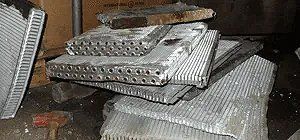 Scrap metal, likely radiator parts, in a dimly lit storage area.