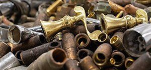 Scrap metal pile, with golden doorknobs and rusted cylindrical components.