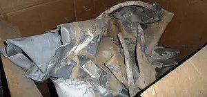 Scrunched, gray metal pieces inside a cardboard box.